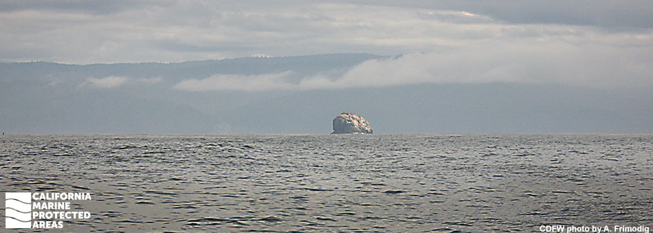 broad view of ocean with a large rounded rock island in the distance